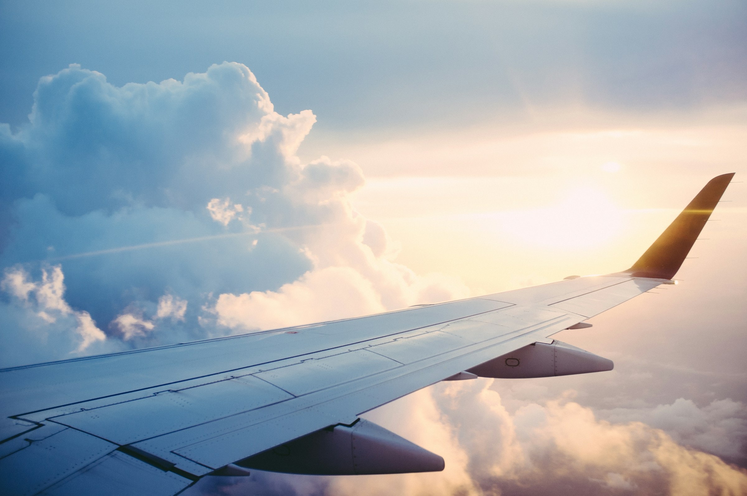 Commercial aircraft flying through dramatic golden hour sky with clouds